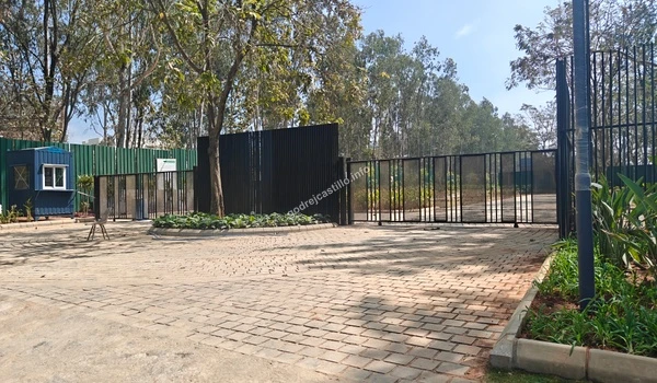 A wide-angle view of the spacious arrival plaza at Godrej Castillo showcasing the circular stone paving and surrounding lush green trees