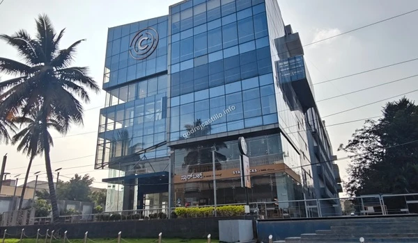 The exterior of a modern commercial structure with palm trees and a Starbucks cafe on the ground level, conveniently close to Godrej Castillo.