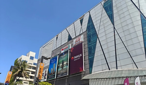 Upward perspective of the distinctive geometric facade at Nexus Vega City mall, a premier shopping destination situated near Godrej Castillo.