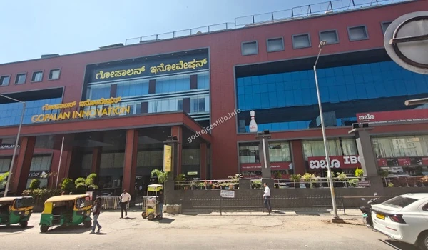 Wide daytime shot of the Gopalan Innovation Mall capturing its vast red facade and glass accents, serving as a recreational hub for Godrej Castillo