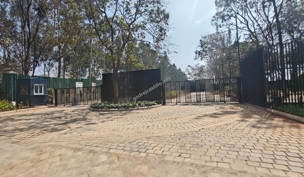 Wide angle view of the grand entrance gate at Godrej Castillo featuring secure black metal fencing and paved driveway