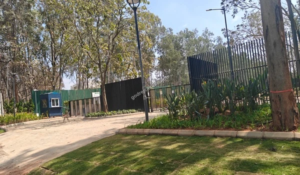 The grand portal of Godrej Castillo featuring a sophisticated black vertical slat gate and a premium cobblestone driveway under a clear sky