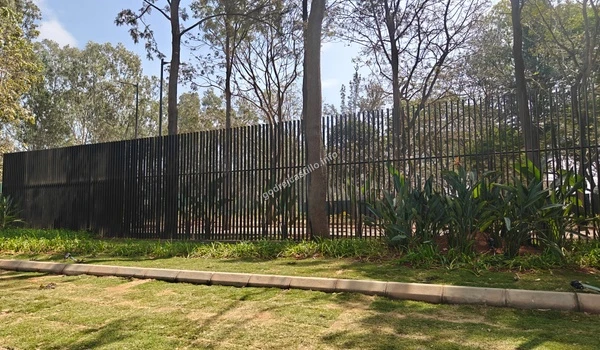 The serene green belt area near the Godrej Castillo entrance featuring mature trees and a well-maintained grassy embankment