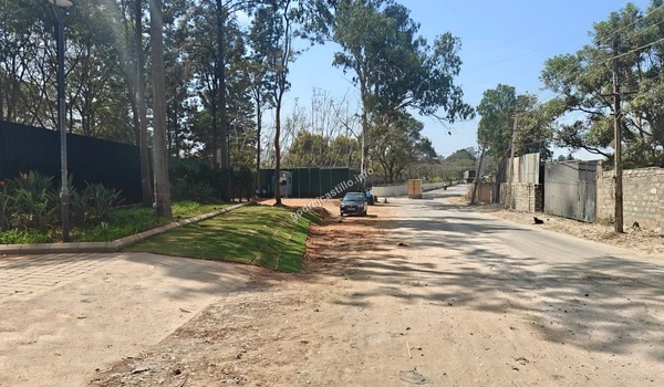 The main site entrance of the Godrej Castillo development, highlighted by green barricading and neatly manicured roadside lawns