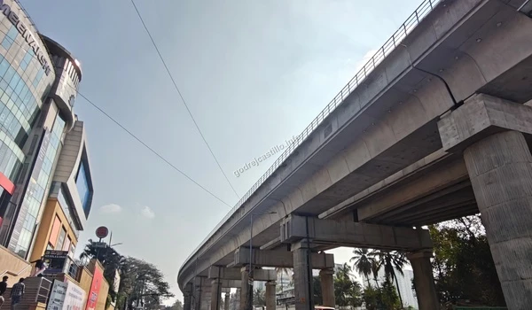 Elevated city metro infrastructure passing alongside commercial buildings, showcasing the prime urban location of Godrej Castillo