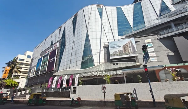 Full exterior view of Nexus Vega City mall highlighting its modern glass and steel facade, offering diverse shopping options for Godrej Castillo residents.