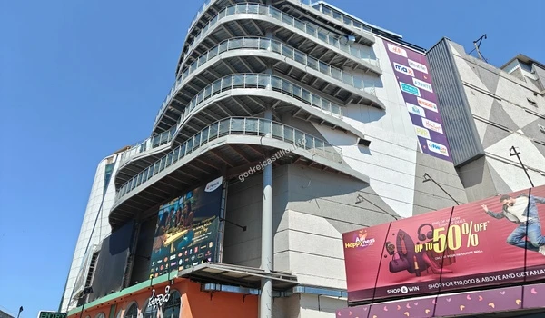 Side view of Nexus Vega City mall highlighting its distinctive tiered outdoor balconies and modern design, situated near Godrej Castillo.