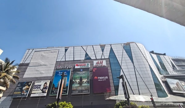Street-level perspective of the sprawling Nexus Vega City mall showcasing multiple brand billboards, easily accessible from the Godrej Castillo project.