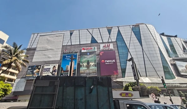 A bustling street view highlighting the prominent Nexus Vega City mall entrance, offering a comprehensive shopping experience near Godrej Castillo.