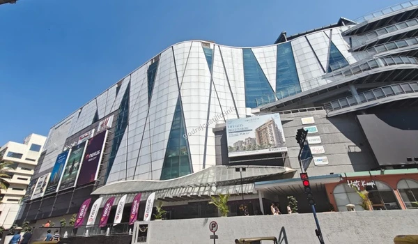 A sweeping view of the massive Nexus Vega City mall structure displaying large real estate and brand billboards close to Godrej Castillo.