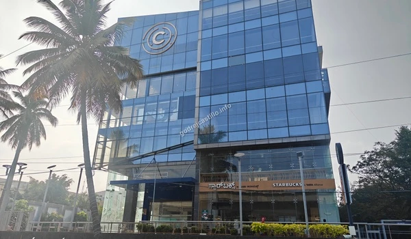 Modern commercial glass building featuring a Starbucks coffee shop on the ground floor, offering premium cafe options near Godrej Castillo